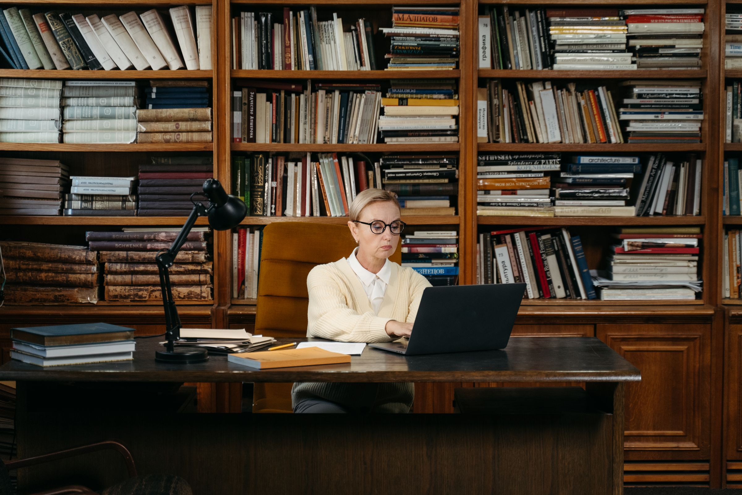 A researcher working on a laptop between library shelves